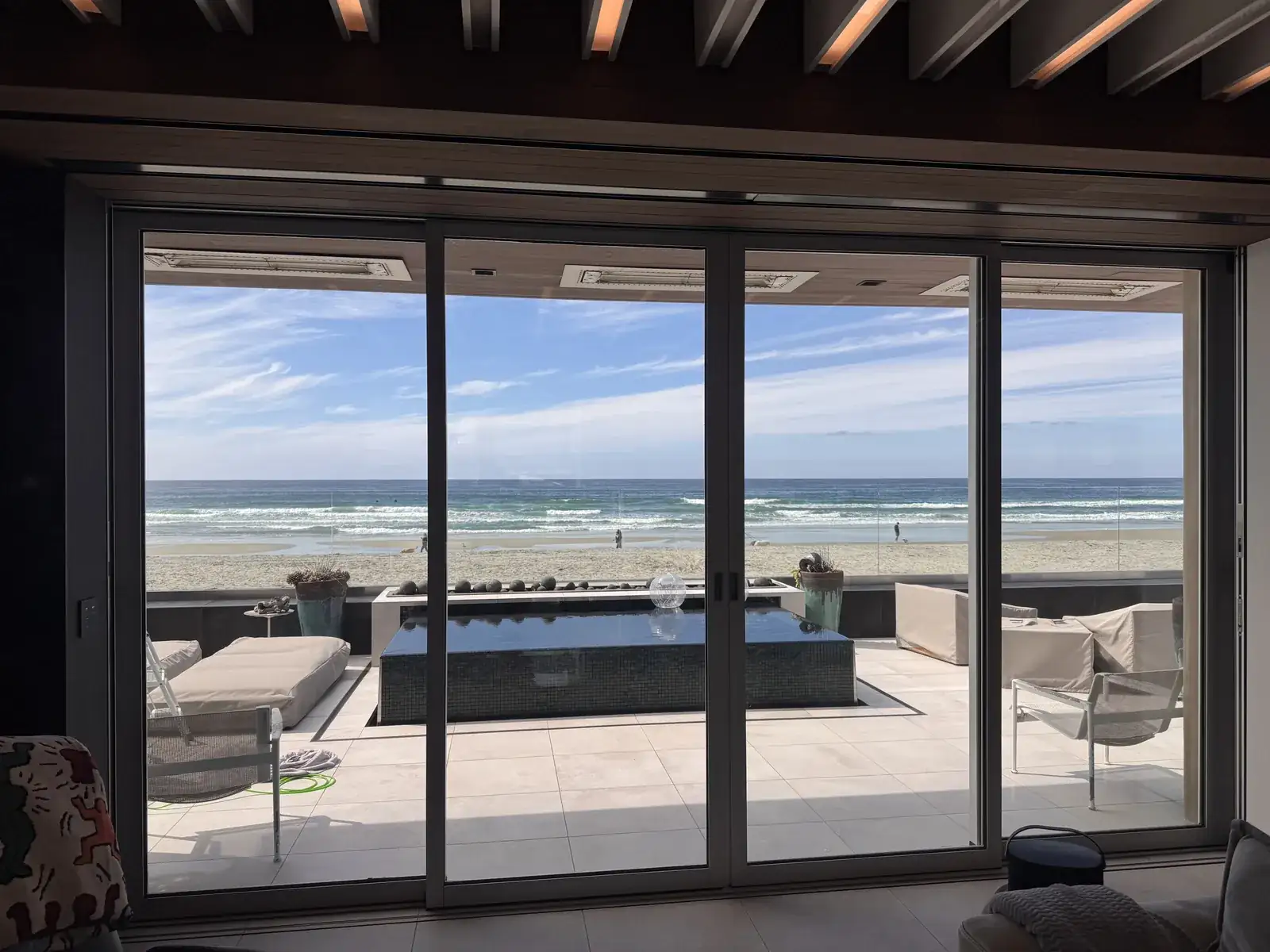 Large glass doors opening onto an ocean-facing terrace in a supplied project photo